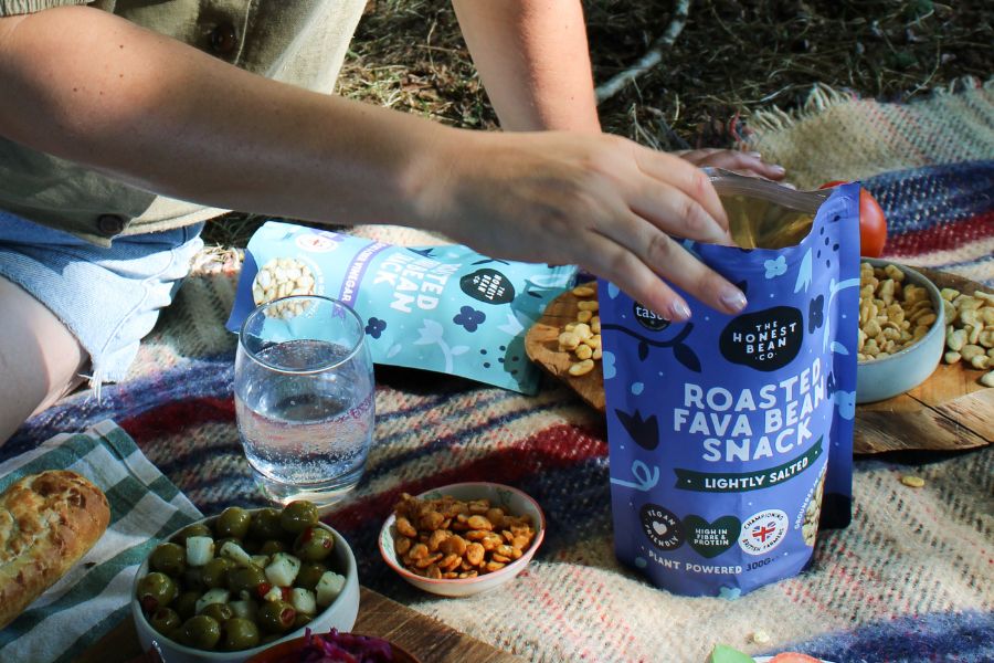 Reaching into a bag of fava beans at a picnic 