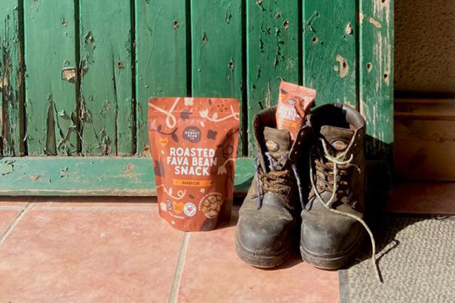 farm boots with fava bean snacks sat at green rustic door