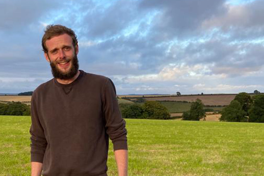 Tom Stephenson standing in field on a farm. smiling man. sunny day. British countryside, Yorkshire.